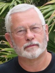 bill brown the author with glasses and white hair against a palm tree background